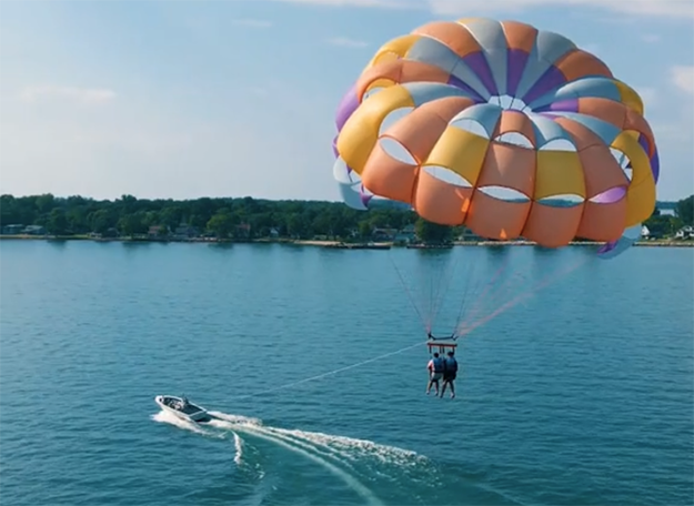 Two people parasailing on a river.